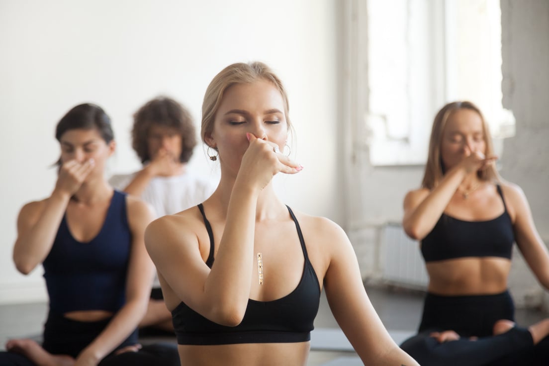 Group of young sporty people making Alternate Nostril Breathing exercise